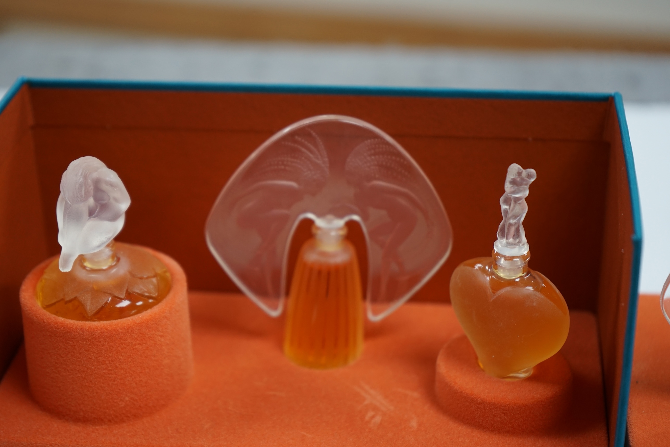 Two Lalique sets of three miniature perfume bottles. 'Les flacons miniatures' 1996-1997 and 1998-2000, boxed and sealed, tallest 7cm high. Condition - good